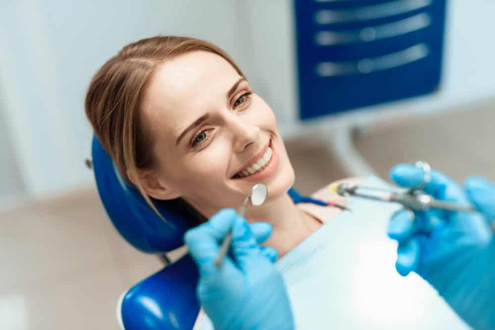 Paziente soddisfatta che guarda il risultato allo specchio dopo il trattamento, simbolo di cure dentali in Albania di alta qualità