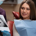 Young woman at dental clinic discussing dental implant options with dentist.